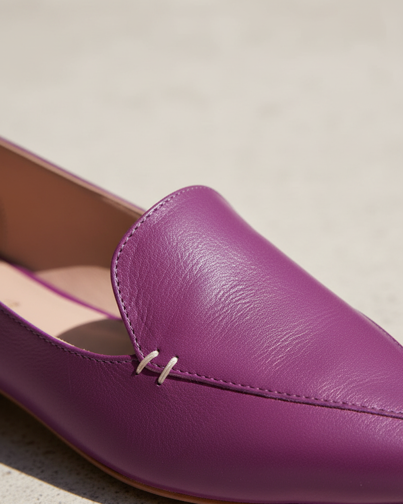 Nahaufnahme von handgenähten Details an Butiá-Ballerinas aus violettem Leder