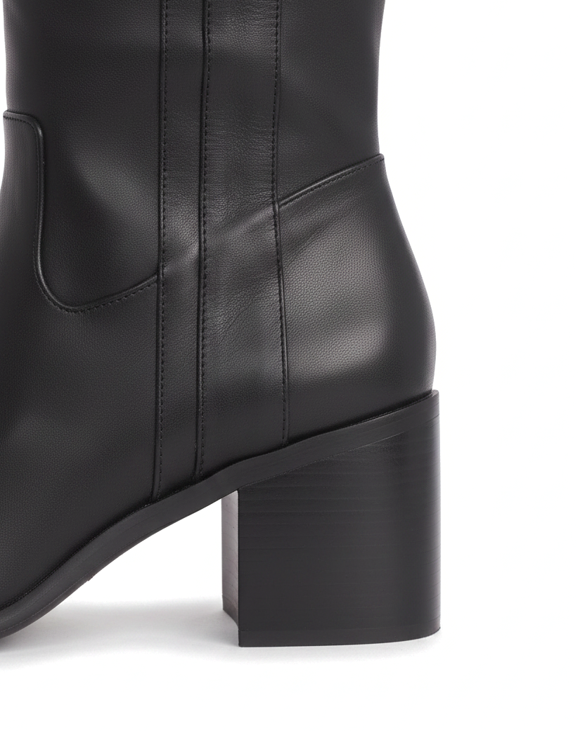 Close up detail of the squared block heel and V shaped ankle panel of the Canna black leather boots
