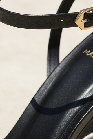 Close-up of Cortica black leather sandal ankle strap gold buckle