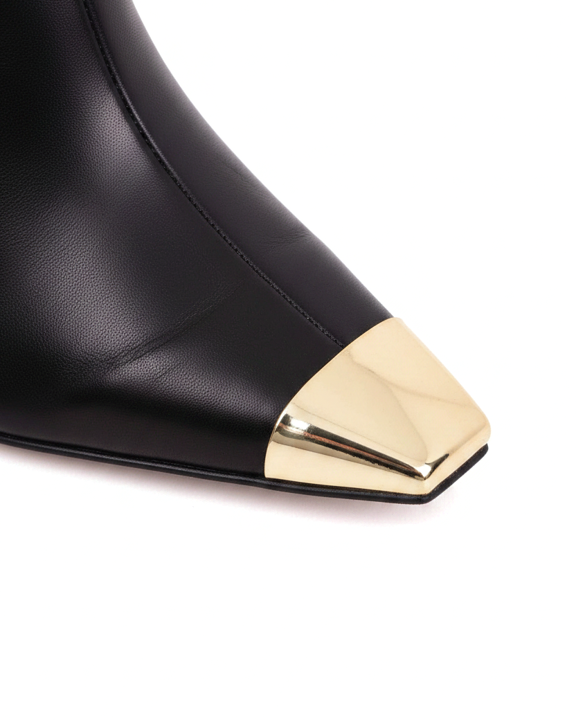 Close up detail of the polished gold metal toe cap against the black leather on the Inga boots