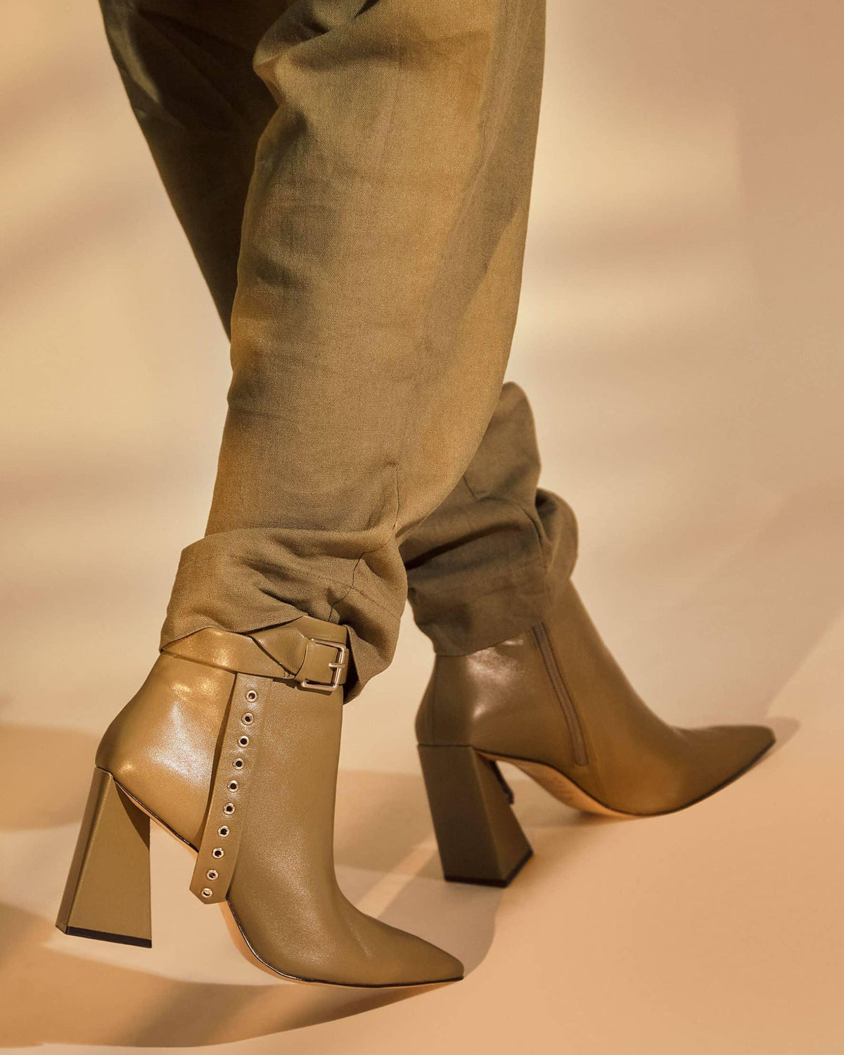 Close view of the silver buckle and eyelet strap on Salvia olive green ankle boots, worn