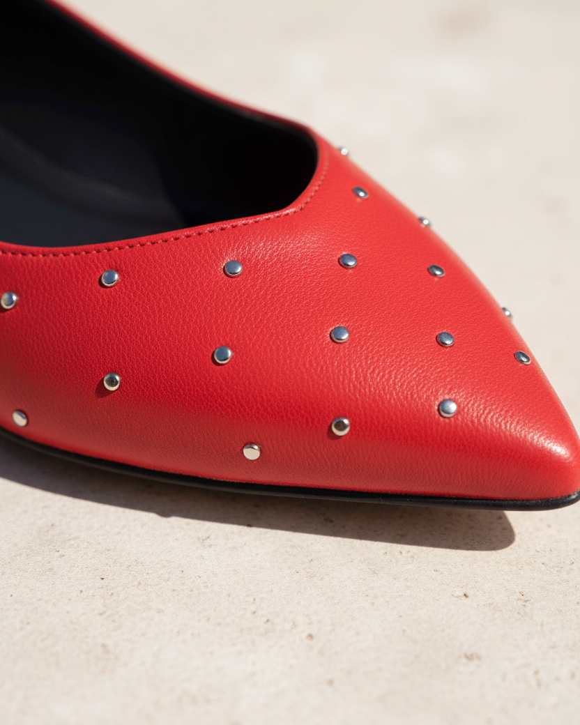 Nahaufnahme eines Hamelia-Ballerinas aus rotem Leder mit verstreuten silbernen Nieten
