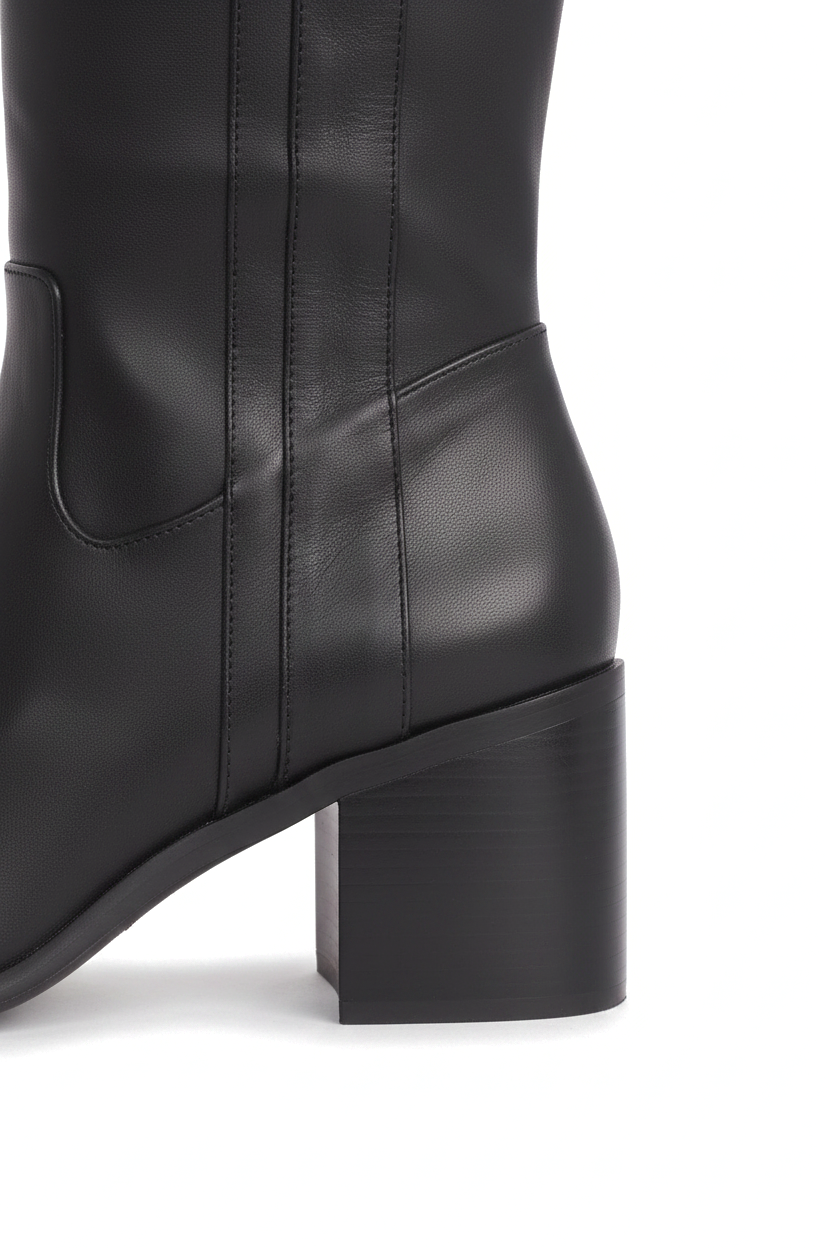 Close up detail of the squared block heel and V shaped ankle panel of the Canna black leather boots