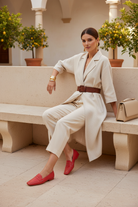 Woman wearing Mangará Cipó red leather square-toe penny loafers with white contrast stitching, seated in an Italian courtyard, side profile view – SKU 201NVCE