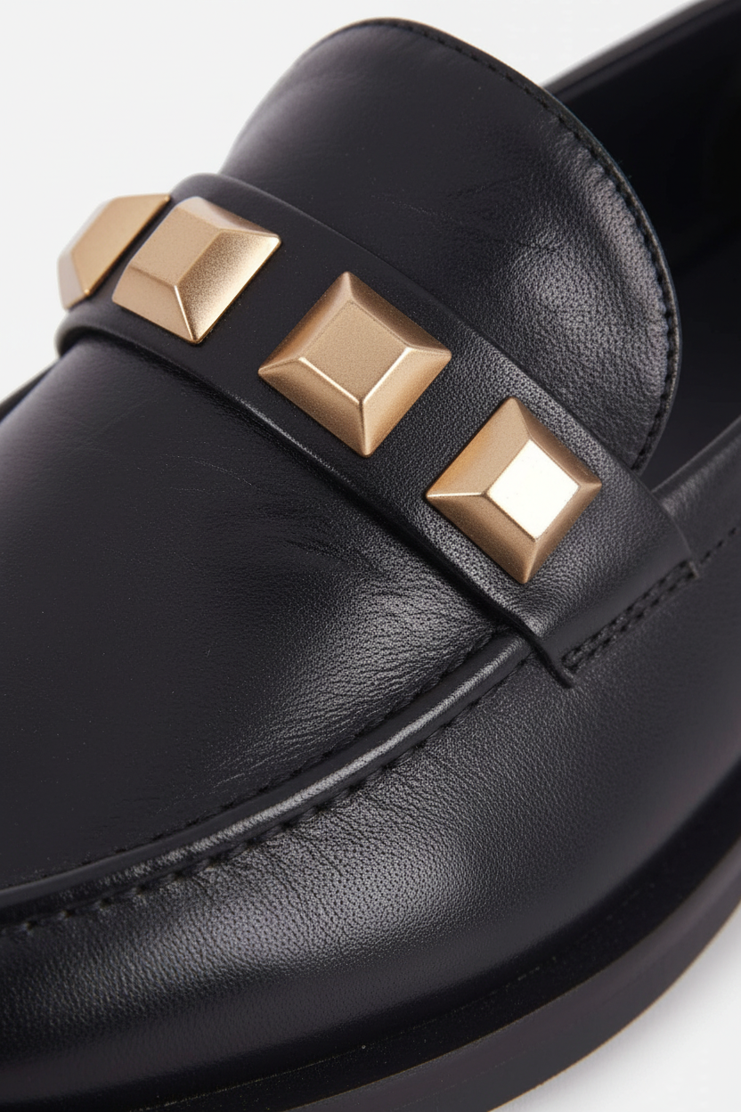 Close up detail of the three gold pyramid studs on the vamp strap of the Caete black loafers