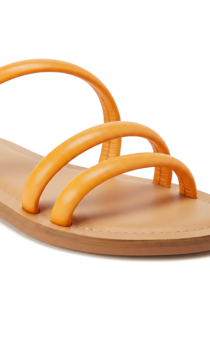 Close-up of the rounded tubular leather straps and natural leather footbed on the Mangará Cacau orange slide