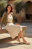 Woman wearing Coroba brown raffia leather ballerinas in a rustic courtyard with olive trees