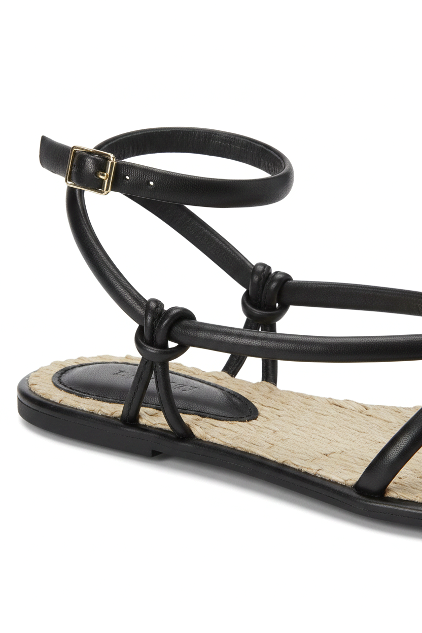 Close-up of the knotted straps, buckle and woven raffia footbed on the Mangará Angico black sandal