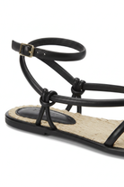Close-up of the knotted straps, buckle and woven raffia footbed on the Mangará Angico black sandal