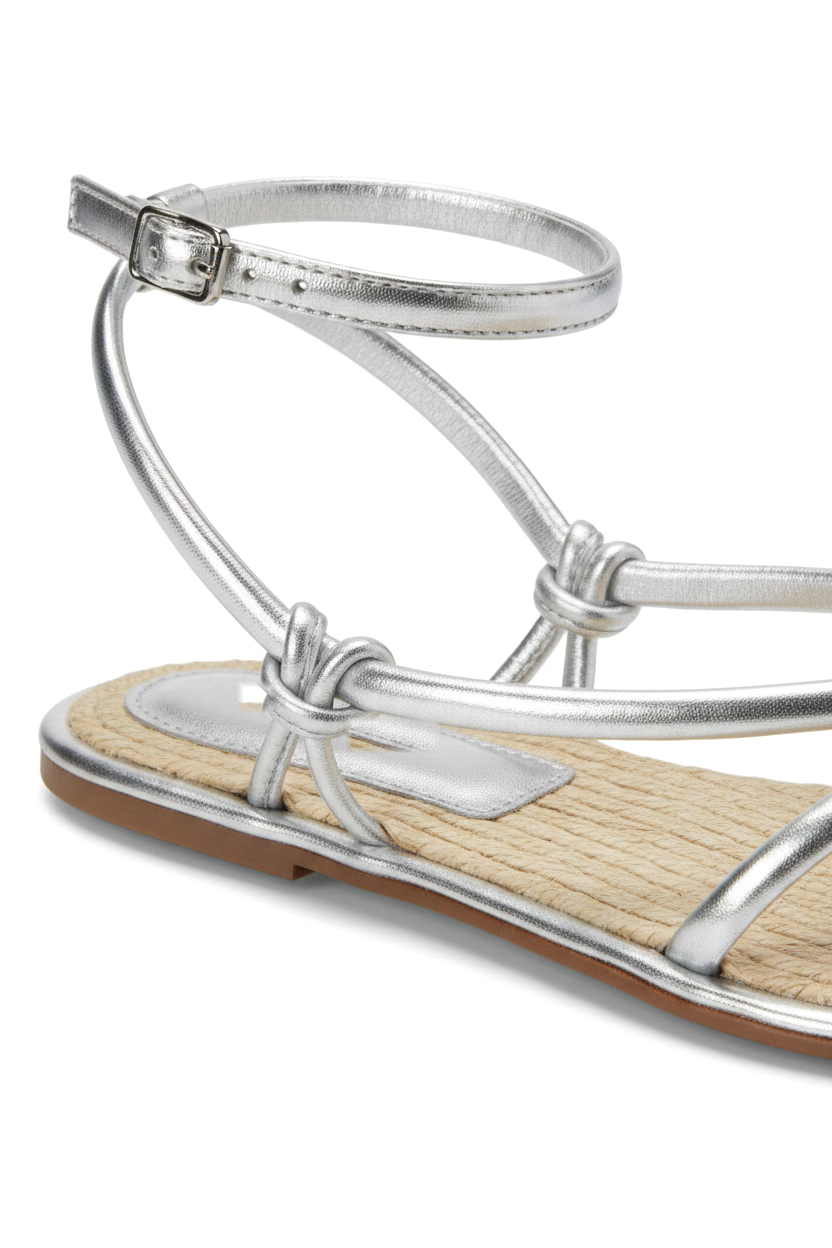 Close-up of the knotted straps, buckle and woven raffia footbed on the Mangará Angico silver sandal