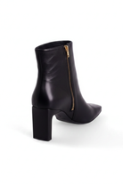 Back detail of Mangará Senna black ankle boot: squared block heel and gold side zip