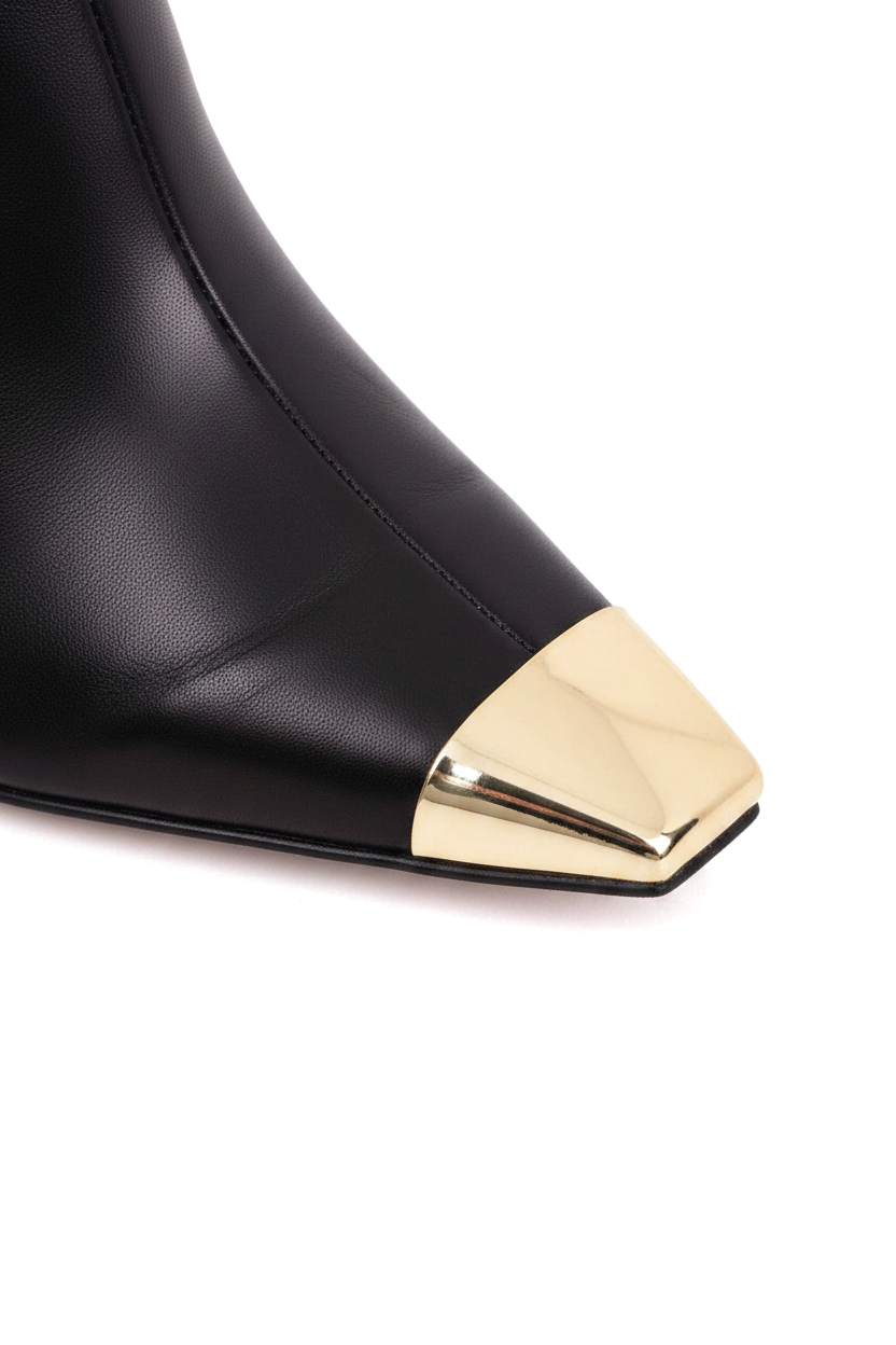 Close up detail of the polished gold metal toe cap against the black leather on the Inga boots