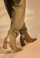 Close view of the silver buckle and eyelet strap on Salvia olive green ankle boots, worn