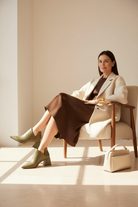 Woman wearing Maranta olive green leather ankle boots in a bright winter interior